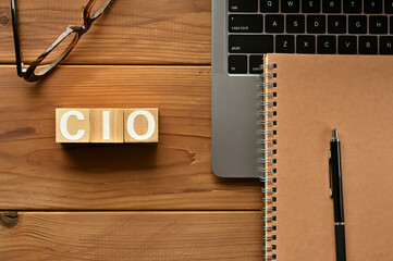 On the table there is a word cube lined CIO with laptop computers and glasses. It is an abbreviation for the word chief information officer.