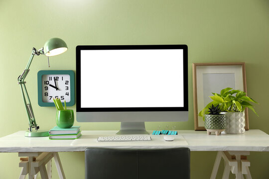 Stylish workplace with modern computer near light green wall indoors. Space for text