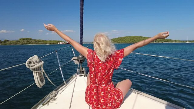 SLOW MOTION: girl in red enjoing the wind on sailboat bow navigating to Telascica and Kornati national parks of Croatia in Europe. Adriatic Sea.
