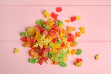 Mix of delicious candied fruits on pink wooden table, flat lay