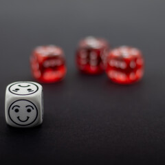 red dice and white dice with emoticon symbols on black background