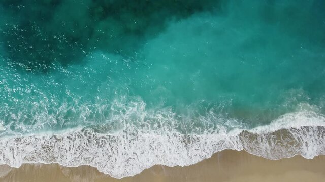 Aerial drone view of powerful waves crushing on tropical beach with yellow sand. Waves breaking on the shore at sunset. Coastline. Beautiful sandy beach at summer. Paradise wild beach, view from above