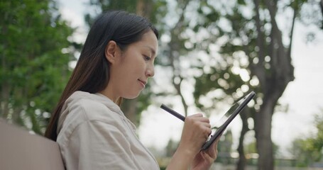 Woman draw on the tablet computer at garden park