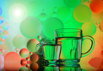 transparent glass with water and oil drops on colored background