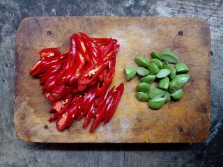 Red chilies and stink beans that have been sliced ​​and placed on a cutting board. Top view.