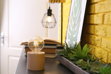 Modern night lamp, houseplants and decor on table in room