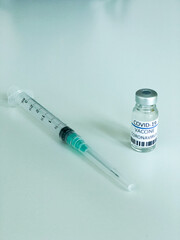 Dose of COVD-19 vaccine and a syringe