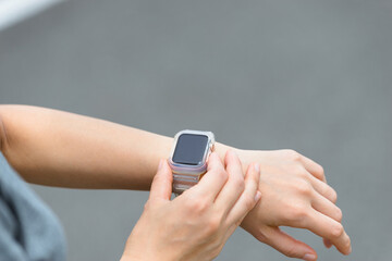 スマートウォッチを見てランニングをする女性