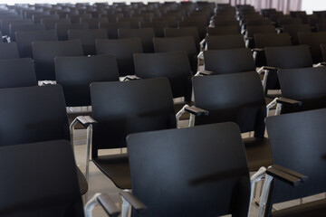 Empty conference hall with rows of black plastic chairs