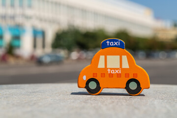 Miniature symbolic toy taxi car against out-of-focus street and building