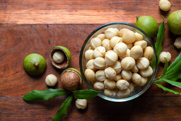 roasted macadamia nut in glass bowl on wooden table background.
