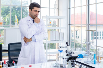 Confident scientist portrait of Happy male scientist keeping arms crossed in a chemistry lab scientist holding test tube with sample in Laboratory analysis background