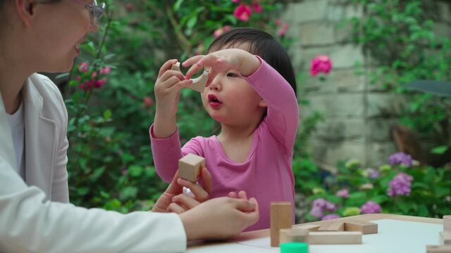 Cute Asian little girl playing with mother in the yard Asian woman and daughter build blocks together slow motion video of happy family lifestyle