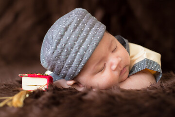 A cute Asian infant Muslim in thobe with prayer cap on bed in home, translation is noble quran