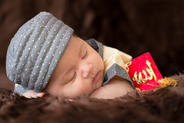 A cute Asian infant Muslim in thobe with prayer cap on bed in home, translation is noble quran