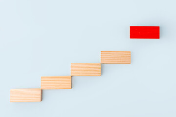 Leadership and influencer concept. Wooden blocks stacking as step stair and following one red on blue background. Individuality and uniqueness. Social distance. Dominant leader.