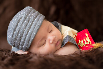 A cute Asian infant Muslim in thobe with prayer cap on bed in home, translation is noble quran