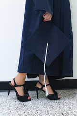 Posando de perfil con tacones, toga y gorro birrete de graduación