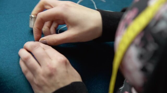 Woman using a needle to stitch specific pattern into traditional jacket