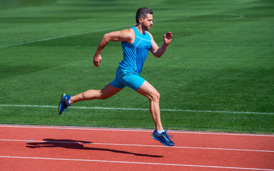 Obraz premium athletic muscular man running in sportswear on stadium track, stamina