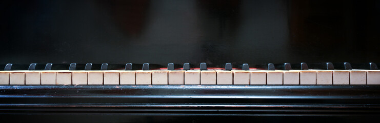 Keyboard of an old grand piano with white and black keys from ivory and ebony, panoramic format...
