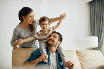Happy parents have fun while playing with their small son at home.