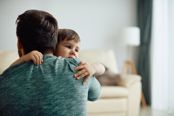 Affectionate little boy and his father embrace at home.
