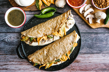 Mexican quesadilla typical food stuffed with mushrooms or chicharron, cheese and squash blossom with sauce in Mexico