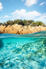Split shot, over under photo. Half underwater with turquoise water and a rocky coast on the water surface. Prince Beach (Spiaggia del Principe) Sardinia, Italy.