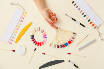 Female hand with nail polish tips and tools for manicure on color background