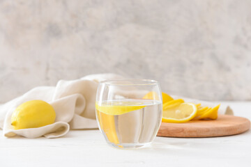Glass with tasty lemonade on light wooden background