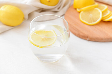 Glass with tasty lemonade on light wooden background