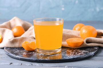 Glass with tasty mandarin juice on color wooden background