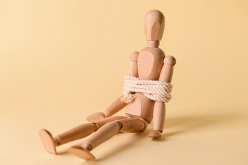 Mannequin with tied around rope on color background. Concept of hostage