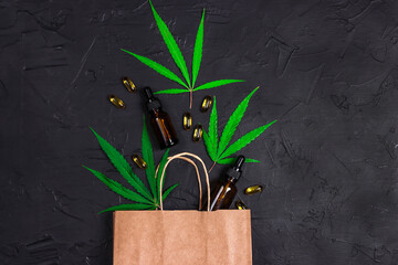 Brown paper shopping bag with green marijuana leaves, Cannabis extract oil in a bottles and...