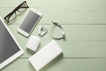 Different modern devices and eyeglasses on color wooden background