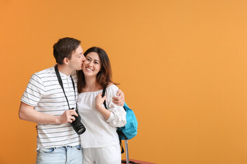 Couple of tourists with luggage on color background