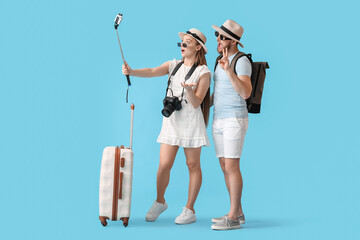 Couple of tourists taking selfie on color background