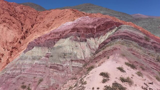 Drone flight above The Hills of Seven Colors showing red, purple, orange, lilac, ocher and beige colors in Jujuy Province, Argentina. Aerial 4K footage.
