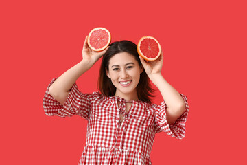 Funny young Asian woman with grapefruit on color background