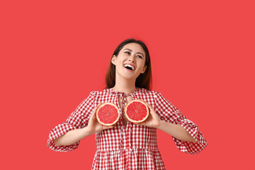 Funny young Asian woman with grapefruit on color background