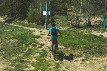 Młody rowerzysta na ebike jedzie lasem pod górę.