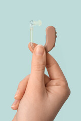 Woman with hearing aid on color background, closeup