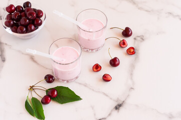 delicious cherry smoothie in glass glasses on a marble table. bowl with fresh cherries.