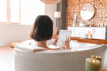 Young woman using tablet computer while taking bath at home