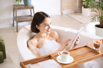 Young woman using tablet computer while taking bath at home