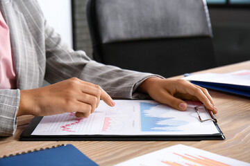Businesswoman with charts at table in office, closeup