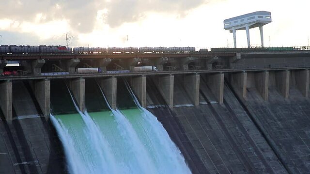 Water discharge at the Bratsk hydroelectric power station. Close-up view of the railway and highway with moving trains and cars.