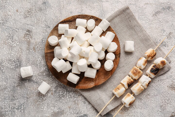 Plate and skewers with tasty fried marshmallows on light background