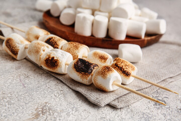 Fototapeta na wymiar Skewers with tasty fried marshmallows on light background